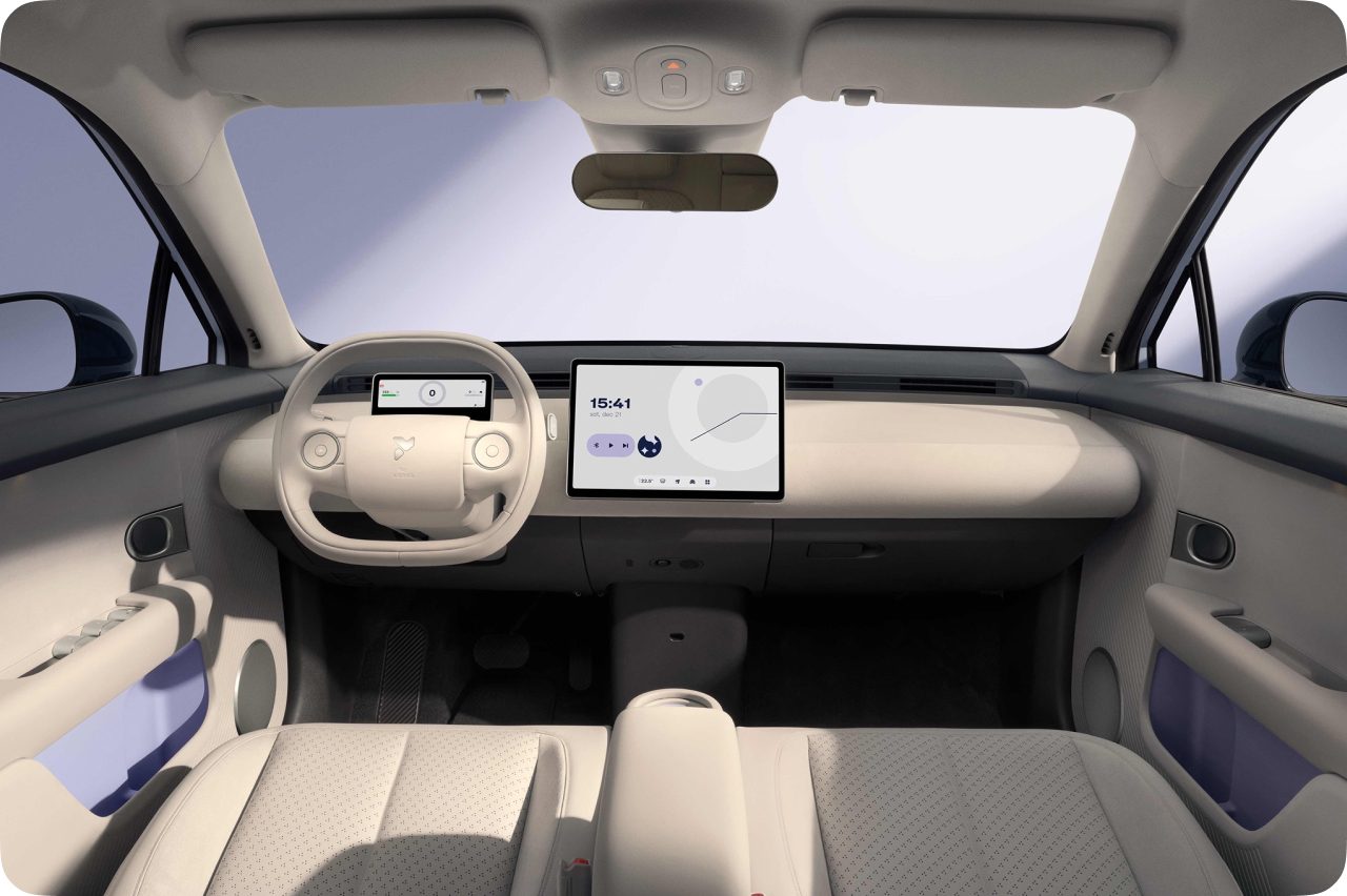 The light travertine interior of a Firefly car: rounded seats, a rounded steering wheel and a rounded dashboard screen.