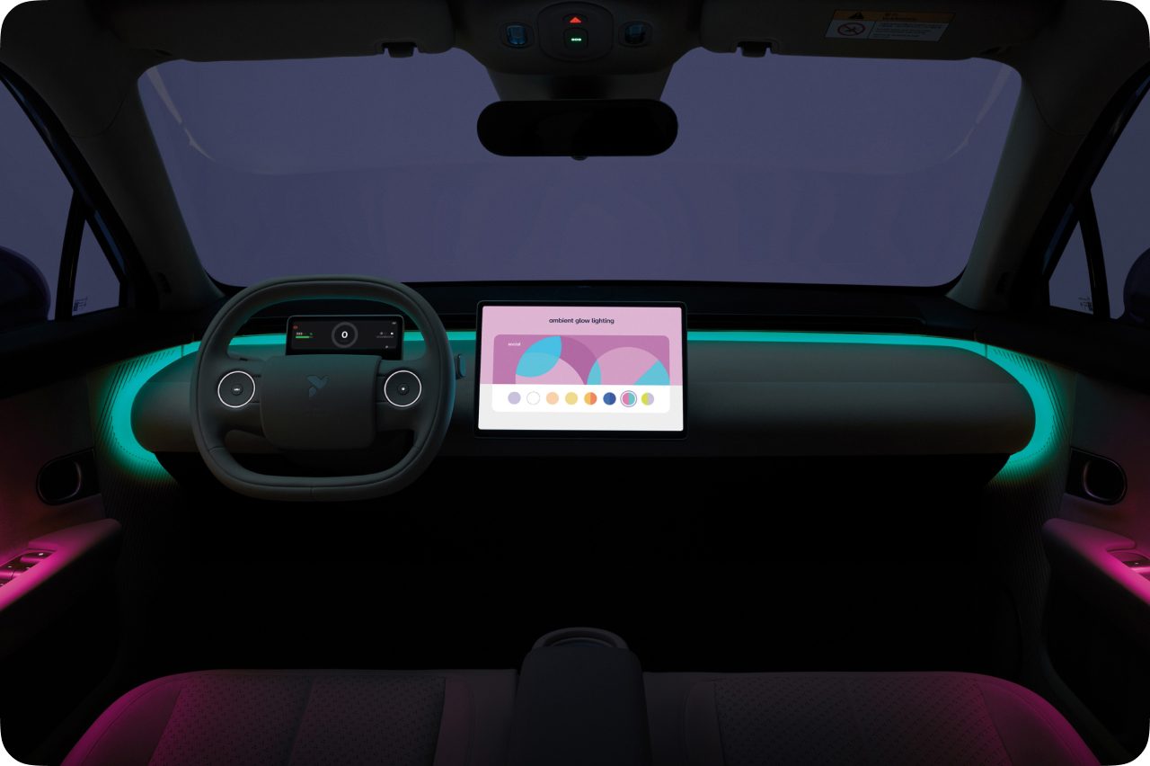 The same Firefly interior at night, with a glowing ambient light strip tracing the rounded dashboard.