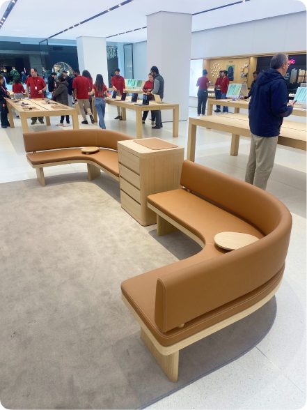 A curved leather bench with rounded ends inside an Apple Store.