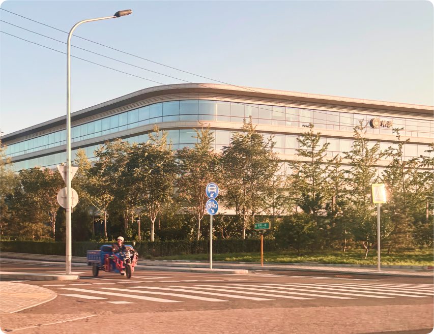 A low office building in China whose glass facade wraps around a rounded corner.